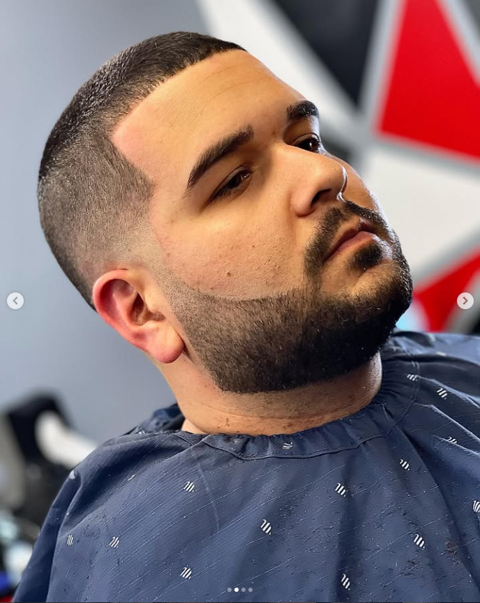 Close-up of a clean skin fade and sharply edged beard against a colorful barbershop backdrop