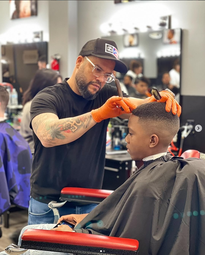 Noel giving a client a haircut in his barbershop